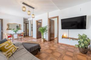 a living room with a couch and a tv on a wall at Casa individual con piscina y barbacoa para visitar Granada in Huétor Vega