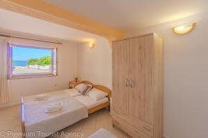 a bedroom with a bed and a window at Zutenica Seaside Residence in Metajna