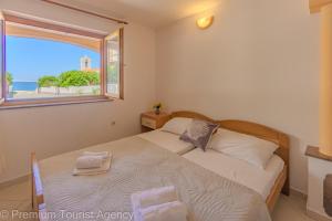 a bedroom with a bed and a window at Zutenica Seaside Residence in Metajna