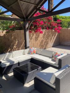 a patio with white wicker furniture and a pergola at Tiki Boho Pool Spa Arcade Mini Golf BBQ in Indio