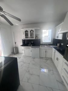een keuken met witte kasten en een grote tegelvloer bij Maison 3chambres avec piscine in Istres