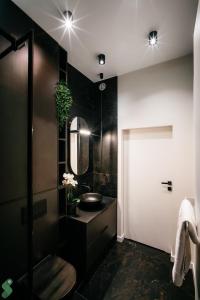 a black bathroom with a sink and a mirror at HANZA Black & White 17th floor SPA & Pool Free Parking by Stayly in Szczecin