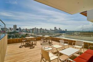 a balcony with tables and chairs and a view of a city at ®{Peaceful~Retreat} @DowntownSD HotTubGymFamily in Santo Domingo