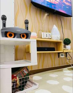 マニラにあるTrees Residence by Gracenzのテレビとハサミが置かれた棚のある部屋