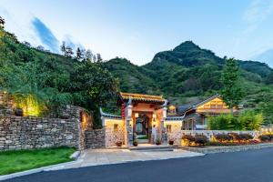 a home in the mountains with a stone wall at Home Away from Home in Zhangjiajie