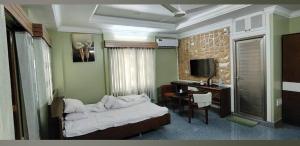 een slaapkamer met een bed en een bureau met een computer bij Dream Holiday Resort in Ināni