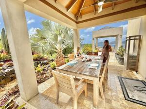 a woman and child sitting at a wooden table on a patio at Window to the Sea - Phenomenal Pool and Hot Tub Villa in East End