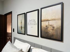 quatro quadros emoldurados numa parede acima de uma cama em Casa com garagem privativa, Perto do Centro em Joinville
