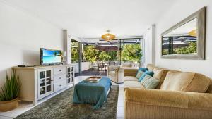 Una sala de estar con un sofá y un televisor. en Seaside On Fourth, en Sawtell