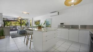 Una cocina con gabinetes blancos y encimera. en Seaside On Fourth, en Sawtell
