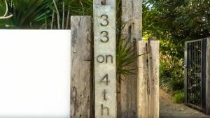 Un cartel en una valla de madera con una puerta. en Seaside On Fourth, en Sawtell
