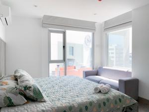 a bedroom with a bed and a couch and windows at Suite de lujo cerca al aeropuerto, terminal, mall sol in Guayaquil