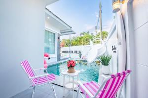 un balcon avec des chaises roses et blanches et une piscine dans l'établissement Bonheur Pool Villa, à Ban Huai Yai