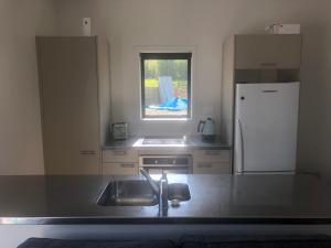 a kitchen with a sink and a white refrigerator at Night Winds Homestay in Ohaupo