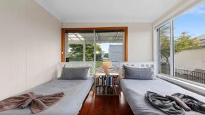 zwei Betten in einem Zimmer mit Fenster in der Unterkunft Ashcroft Cottage in Nambucca Heads + 7 Fotos