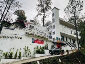 兰斯顿The Shalam Resort श्रीकृष्ण शरणं मम的一辆停在白色建筑物前的汽车