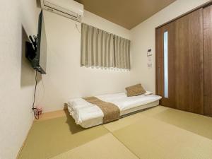 a bedroom with a bed and a television in it at HANASTAY花渓居 · 川（KAWA） in Osaka