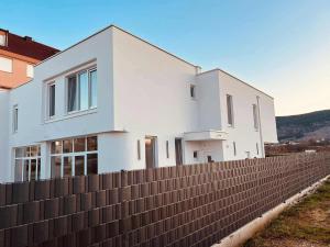 a white house behind a fence at Apartmani Leon in Međugorje