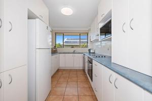 una cucina con armadietti bianchi e pavimento piastrellato di Sea Gaze 3 - With Remarkable Ocean Views a Kingscliff
