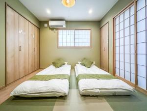 two beds in a room with two windows at HANASTAY花渓居 · 尺八（SYAKUHACHI) in Osaka