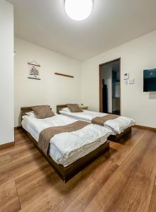 two beds in a large room with wooden floors at HANASTAY花渓居 · 浦（URA) in Osaka