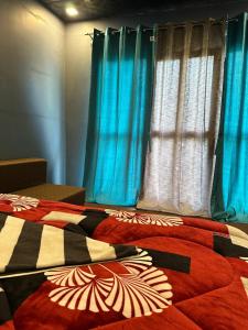 a bed with a colorful comforter and blue curtains at Harsil Heights in Harsil