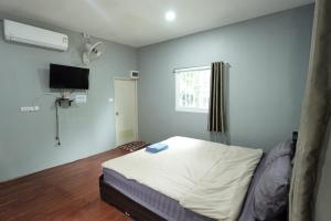a bedroom with a bed and a television and a window at NP โฮมสเตย์ นอนเต็นท์ติดแอร์ in Ban Kaeng Manao