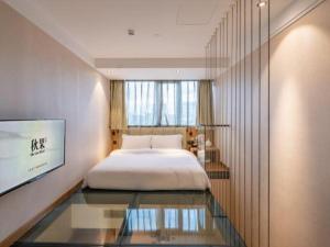 a bedroom with a bed and a tv on a wall at Qiuguo Hotel Beijing 789 Art District in Beijing