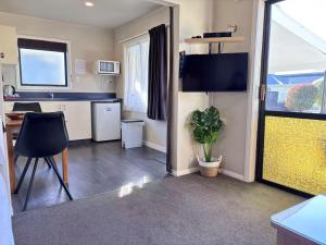 a room with a kitchen with a table and a tv at Arcadia Motel in Nelson +77 photos