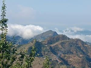 a view of a mountain with clouds in the background at Jai Bholenath home stay in Jageshwar