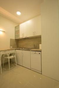 Apartments Jevremova في بلغراد: مطبخ بدولاب بيضاء وطاولة ومغسلة