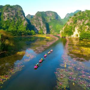 a group of boats floating down a river with mountains at Hoa Lư City Hotel in Ninh Binh