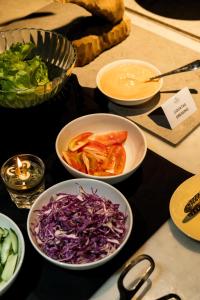 una mesa cubierta con tazones de hortalizas y otros alimentos en Sunday Hotel Arshika Sunset Road, en Kuta