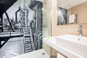 a bathroom with a mural of a factory at NH Essen in Essen