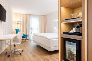 a hotel room with a bed and a desk and a room at NH Essen in Essen