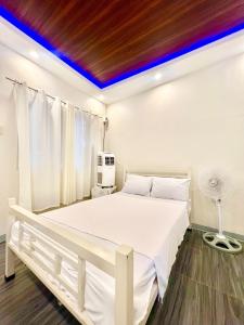 a white bedroom with a white bed with a blue ceiling at Lipa City Transient Room in Inosloban
