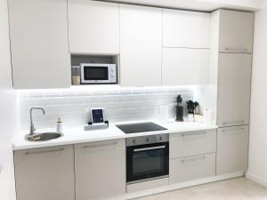 a white kitchen with a sink and a microwave at Шикарні апартаменти м Мінська 10 хв пішки, 3 поверх, Богатирська 6А in Kyiv +3 photos