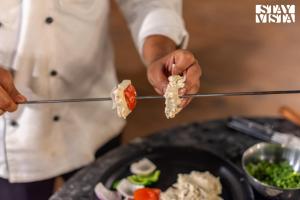 eine Person, die ein Stück Essen auf einer Zange hält in der Unterkunft StayVista at Alpine Bliss - Home Theatre, Bonfire in Masuri