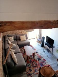 a living room with a couch and a tv at La Terrasse des Moulins Maison de Charme in Saint-Félix-Lauragais