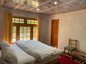 a bedroom with a bed and a chair and a window at Brookfall resort khaplu in Khaplu