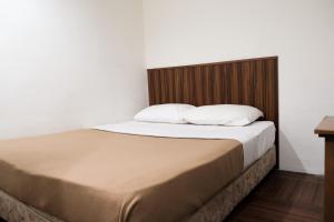 a bed with a wooden headboard and white pillows at Impress Star Hotel in Kampong Saleng