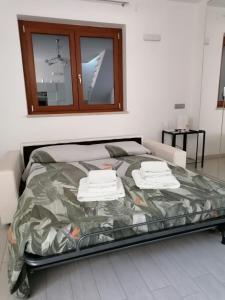 Una cama en una habitación blanca con toallas. en Fabiola home, en Borgo Montenero