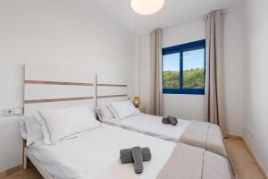 two beds in a white room with a window at Brisa del Puerto de la Duquesa in Manilva +17 photos