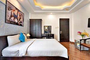 une chambre avec un grand lit blanc et un bureau dans l'établissement S79 Crowne Bui Vien, à Hô-Chi-Minh-Ville