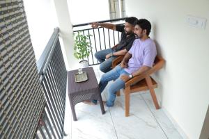 Dos hombres sentados en un balcón mirando por una ventana. en Palm Paradise Beach Resort Varkala, en Varkala