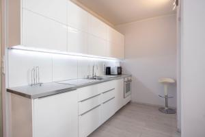 a white kitchen with white cabinets and a sink at Sunhill Luxury apartman at Buda Castle in Budapest +4 photos