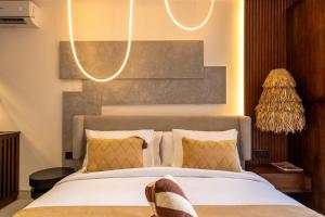 een slaapkamer met een groot bed met witte lakens en kussens bij Palermo Suites by Betterplace in Ubud +57 foto's