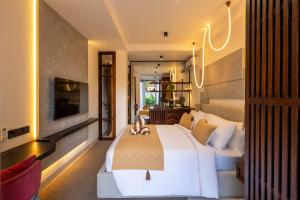 een slaapkamer met een groot wit bed en een tv bij Palermo Suites by Betterplace in Ubud