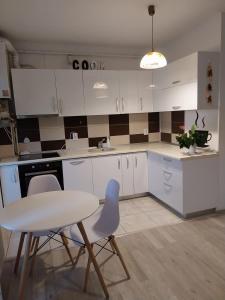 a kitchen with white cabinets and a table and chairs at Ianca Urban Stay in Şelimbăr