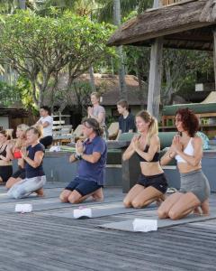 a group of people sitting on mats in aorative yoga pose at Qunci Villas Resort in Senggigi